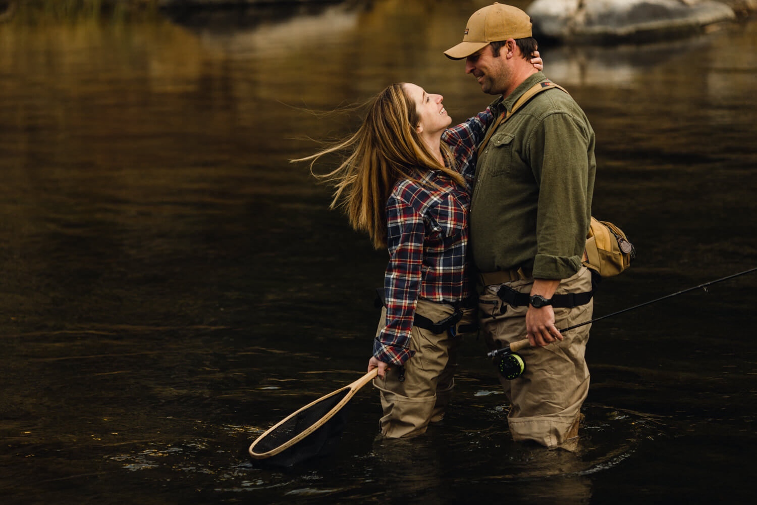 Fly fishing couple leans in for a kiss.