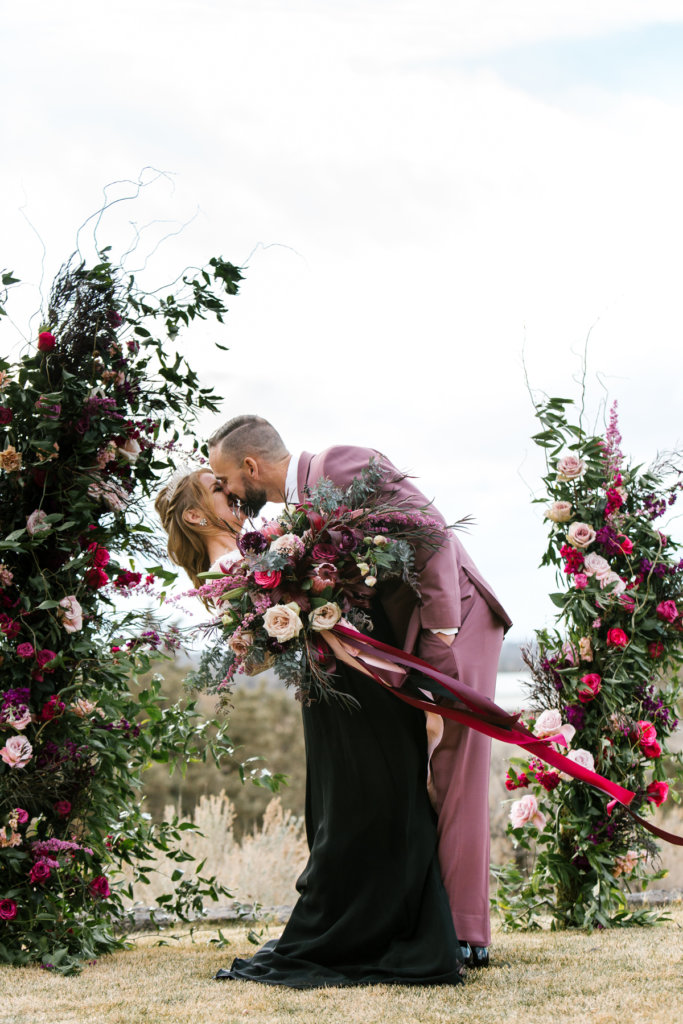 Brasada ranch, Central Oregon. Couple kissing in front of floral arch.