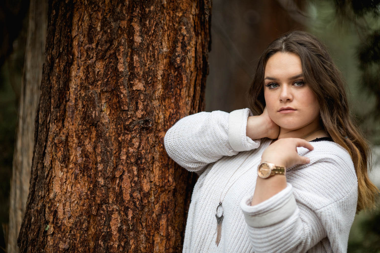 Senior picture of a girl leaning against tree trunk.