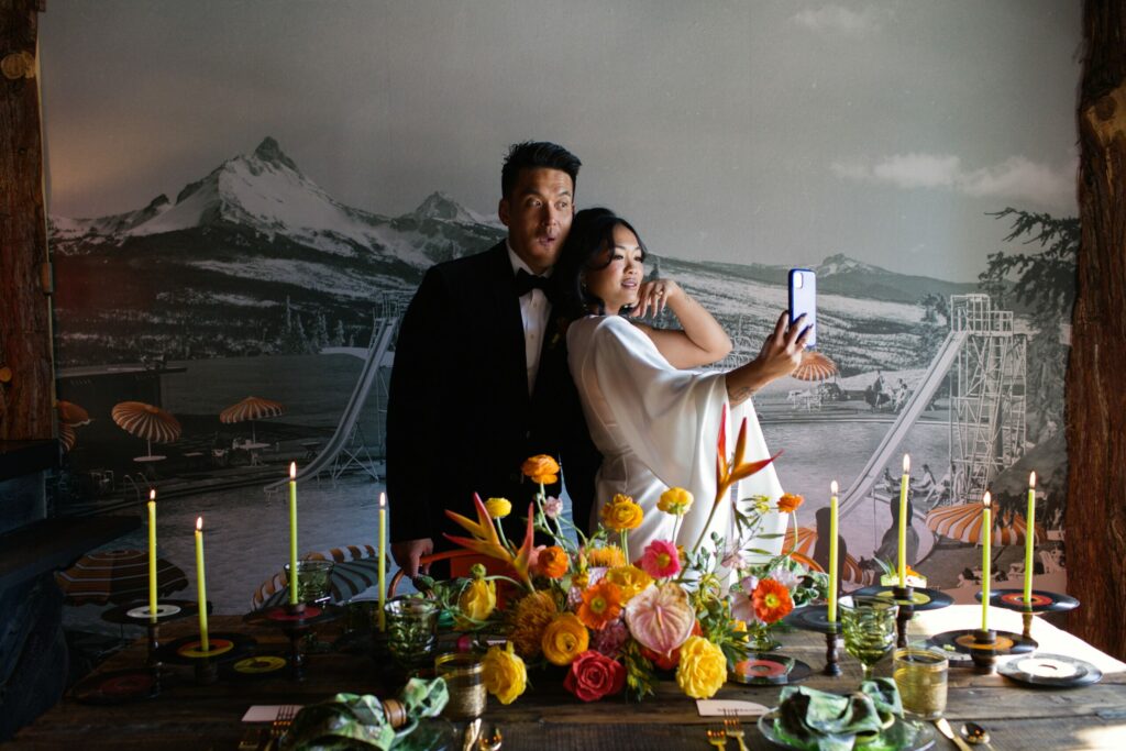 Couple takes a selfie behind reception table.