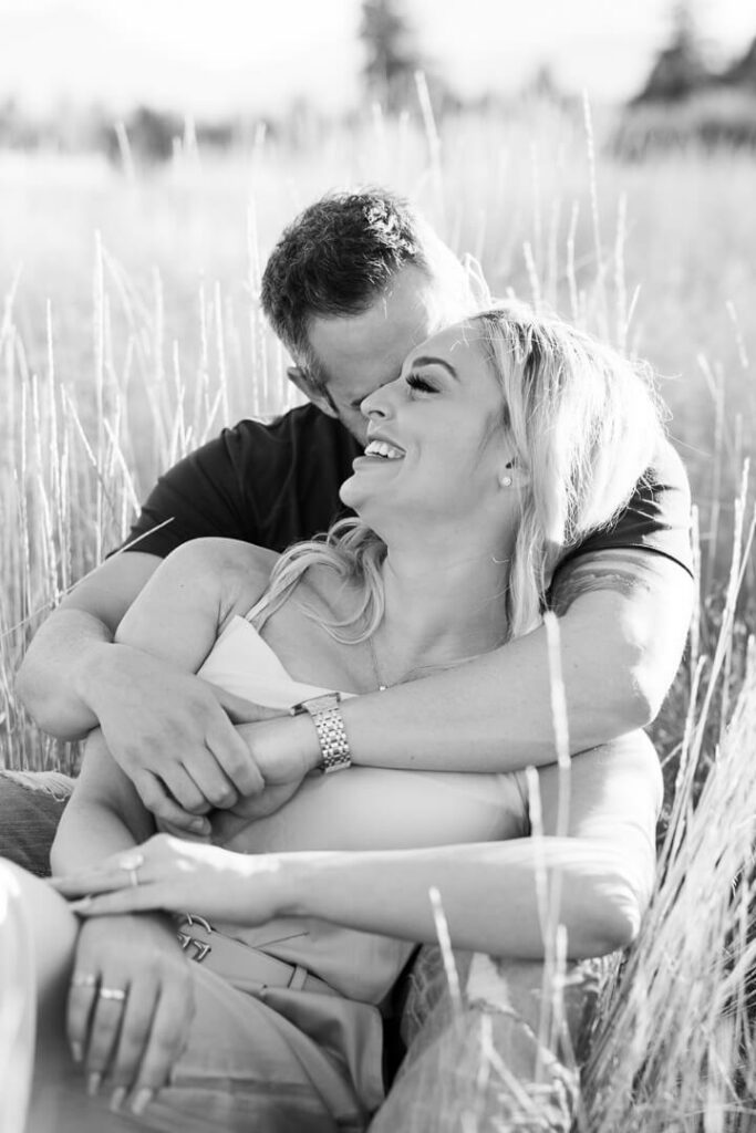Black and white image of a couple laying in a field.