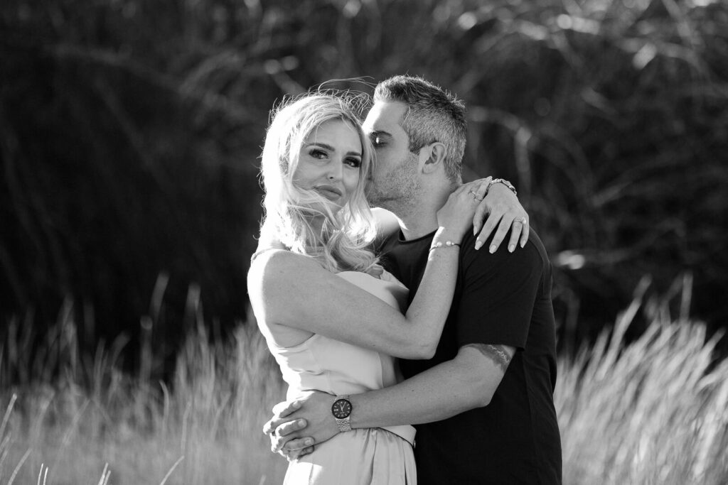 Black and white image of a quiet moment with man kissing woman's cheek.