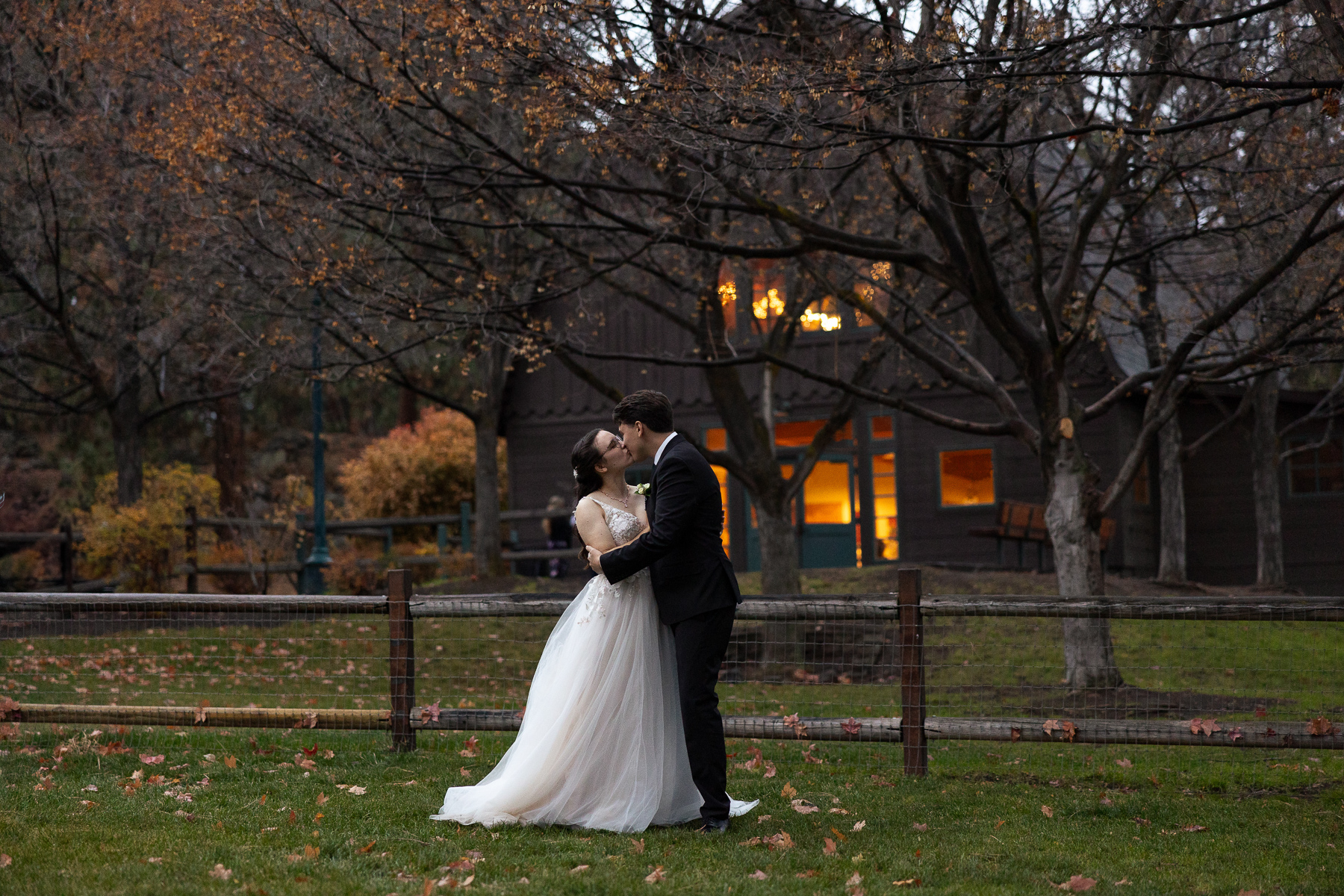 Couple kisses at dusk with Hollinshead Barn in the background.