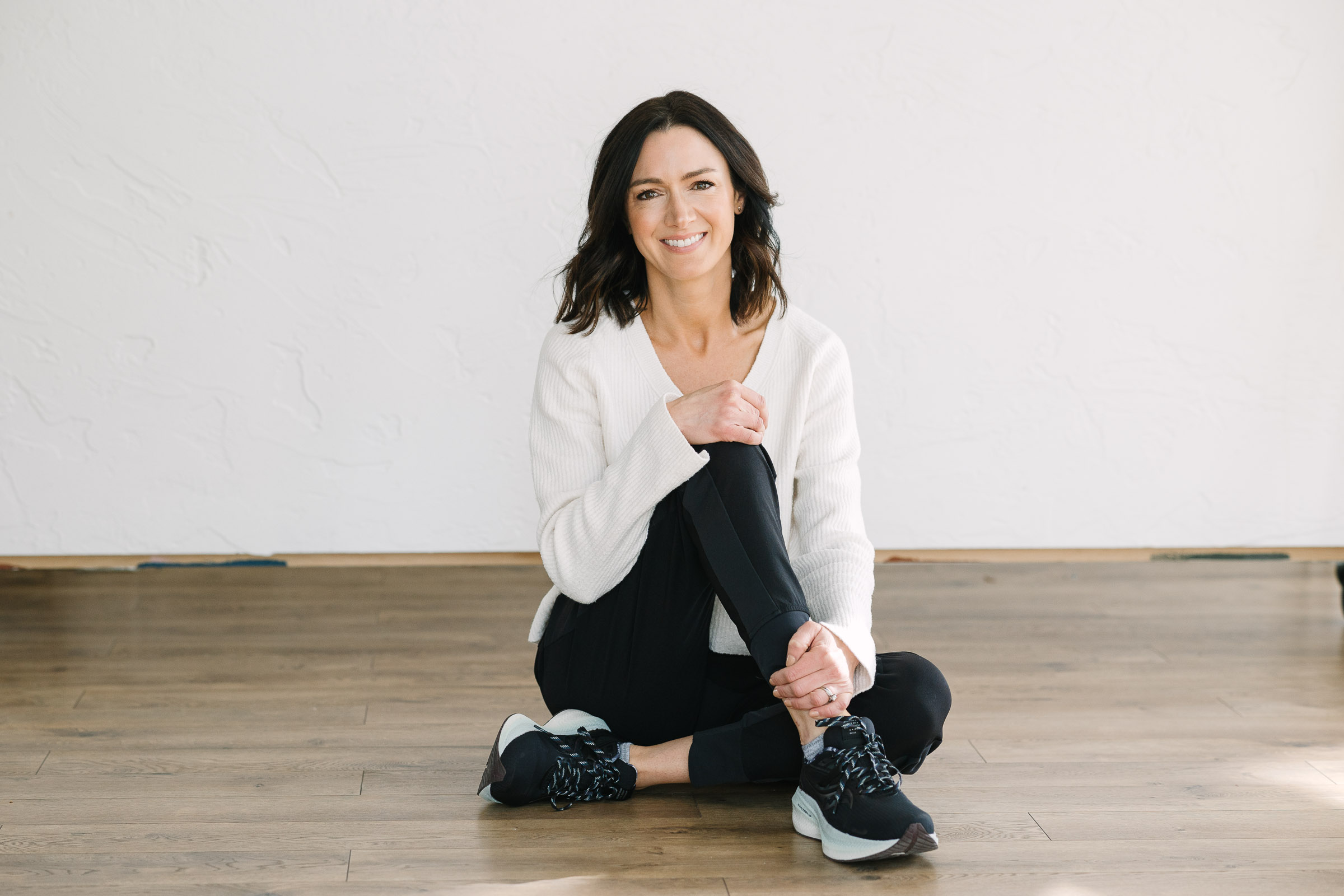 Woman sits on floor with legs crossed and knee up.