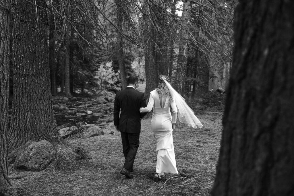 Black and white image of a quiet moment where the couple walks into a wooded area at Black Butte Ranch. 