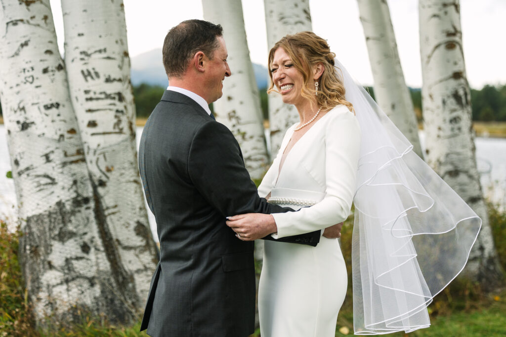 An emotional moment between the bride and groom during their first look. Aspen tree trunks are in the background. 