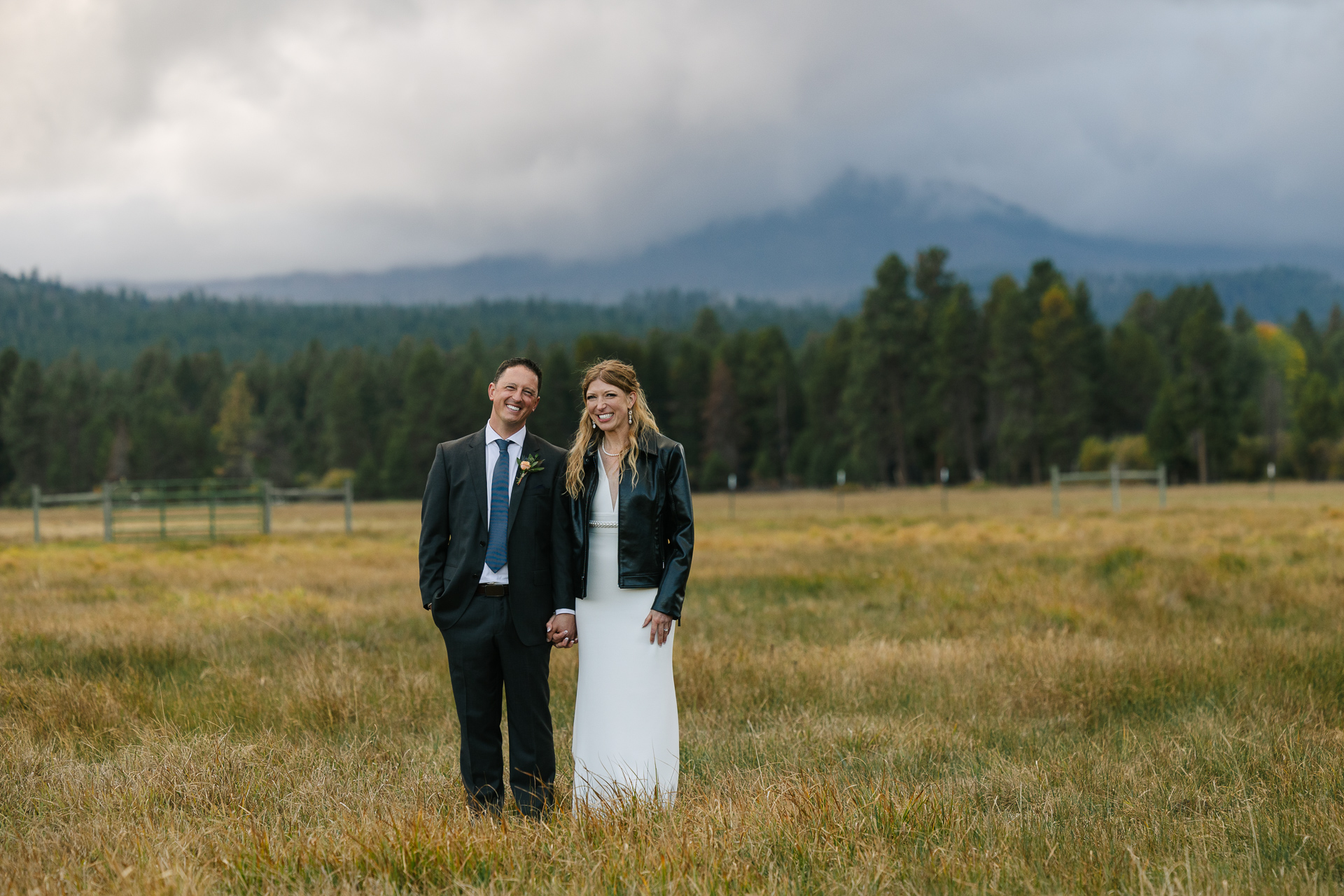 Newlywed couple smiling in field post wedding ceremony. 