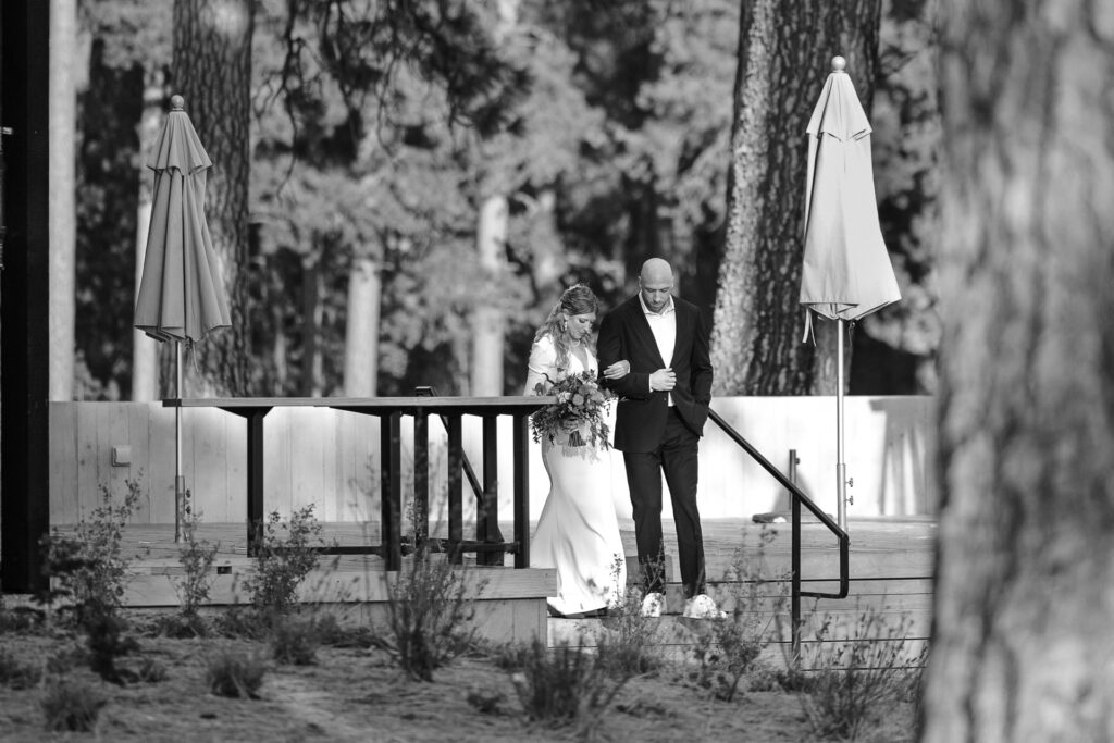Bride emerges from Black Butte Ranch Lodge with her brother to walk down the aisle. 