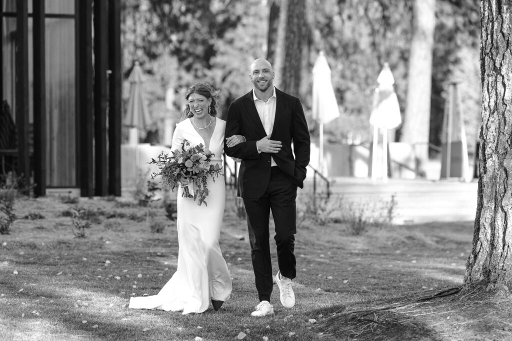 Bride walks across lawn with her brother. Black and white image.