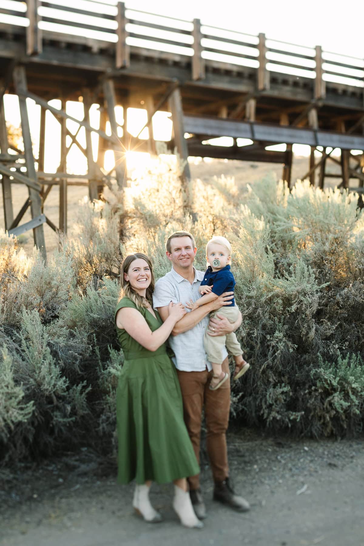 Family near trestle bridge at Brasada Ranch as the sun sets behind the sage brush and bridge.