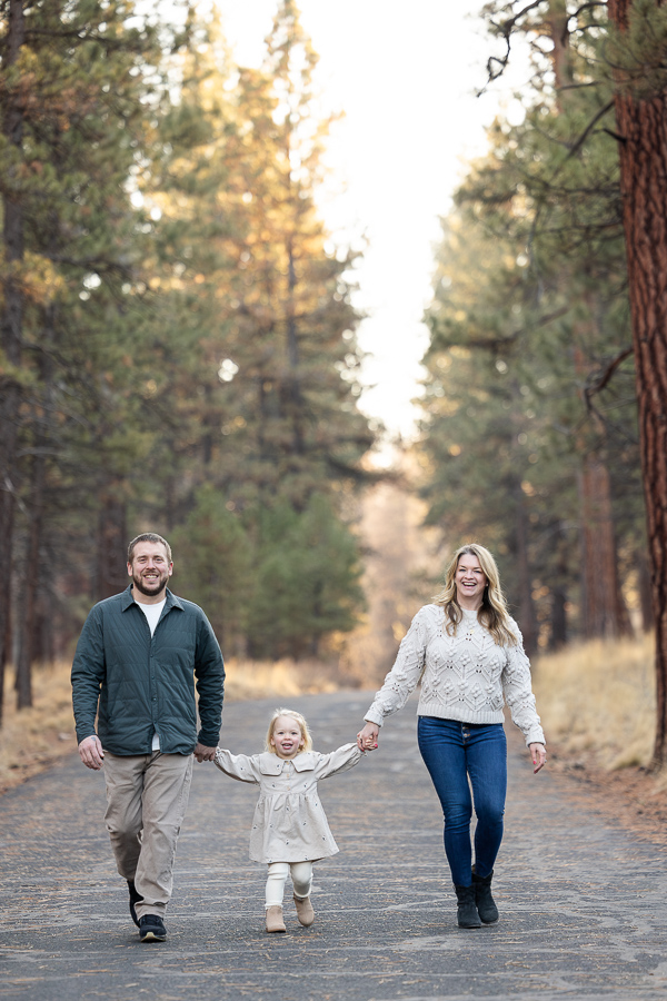 Family of three holds hands and walks down path at Shevlin Park.