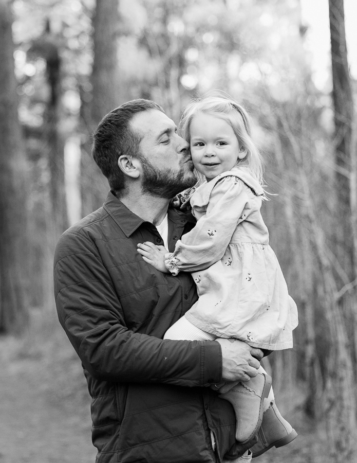 Black and white image of father kissing cheek of daughter.