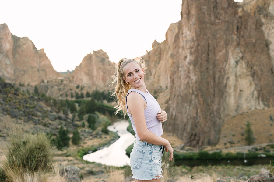 Girl poses for camera overlooking Smith Rock Park. The rocks and river are in the background.