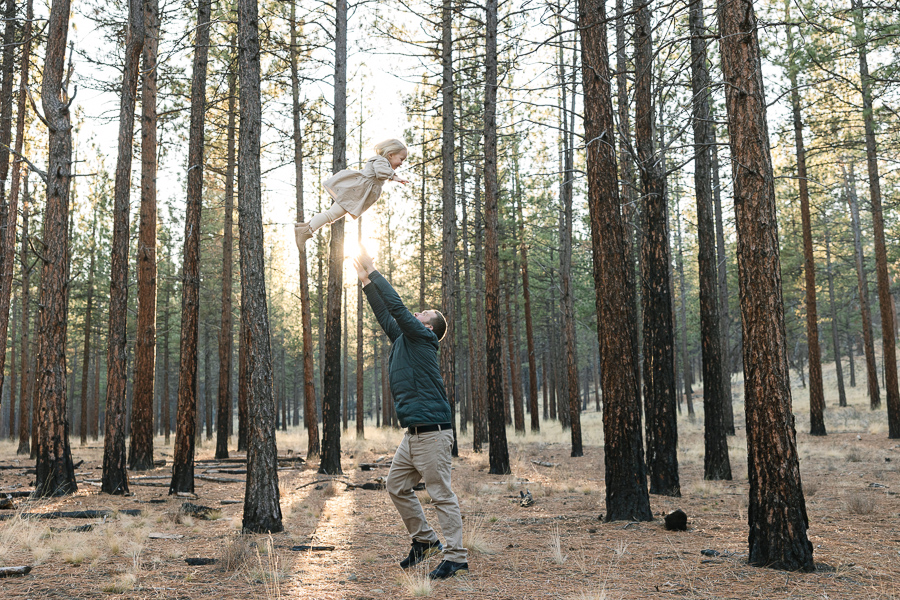 Hand tosses young girl high in the air and she smiles and laughs joyfully.