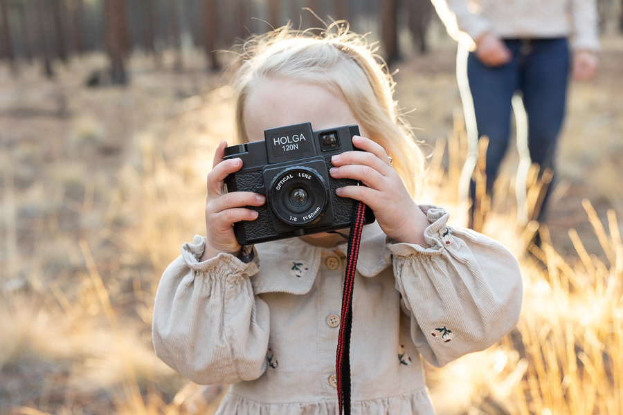 Young blonde girl holds camera.