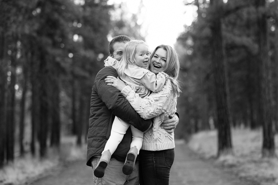 Black and white photo of a young family hugging each other filled with joy.