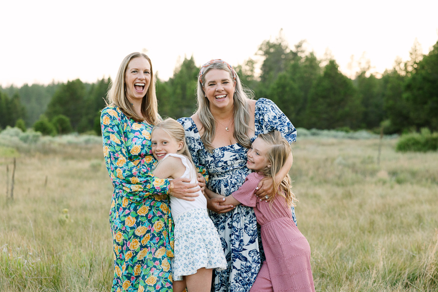 Two young blonde girls hung their moms while giggling.