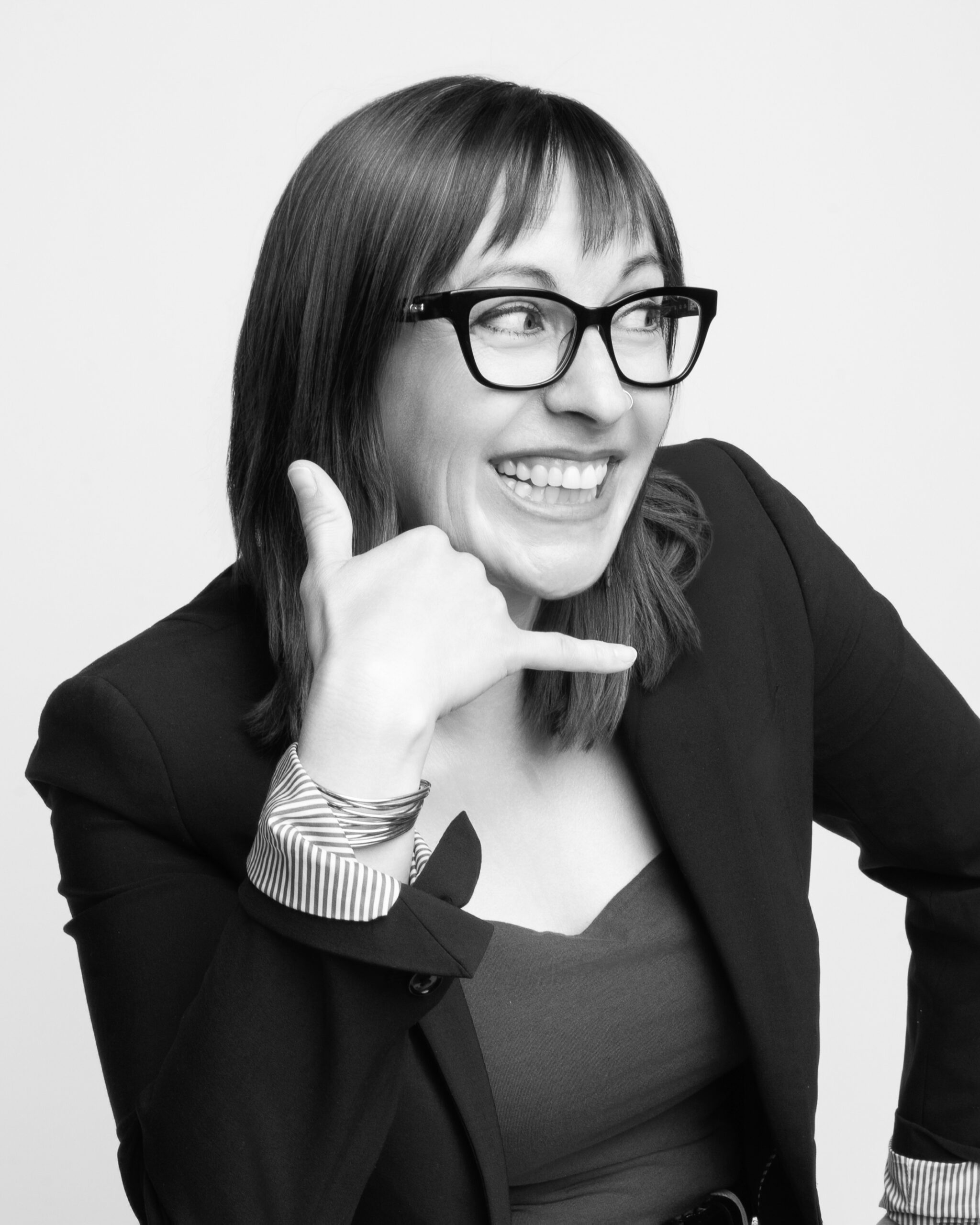 Black and white photographer of Gwen holding invisible phone to mimic "call me."