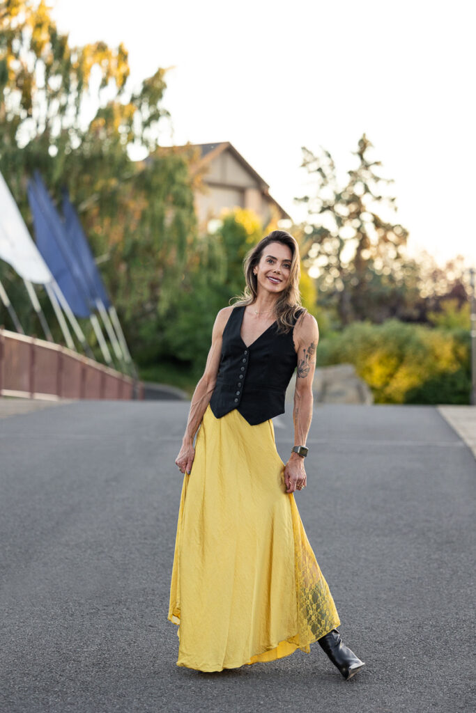 Brunette photographed in black vest and chartreuse skirt.